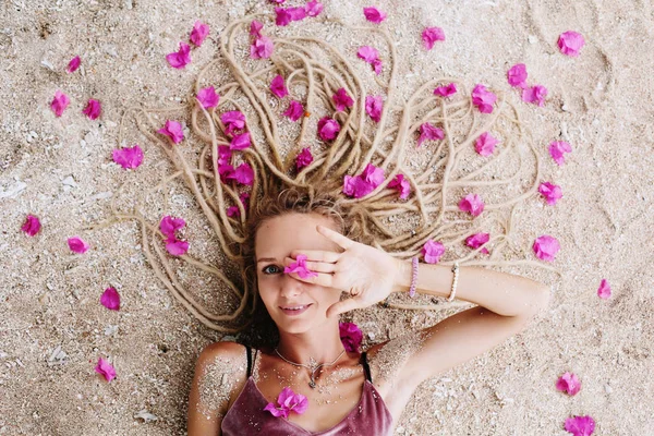 Молода Жінка Дредлоці Стиль Волосся Лежить Морському Березі Рожевими Квітами — стокове фото