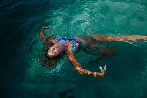 Woman swimming relaxing in tropical swimming pool outdoor. Summer sunny  day