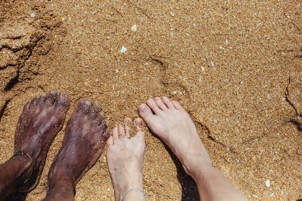 海の砂の上の混合レースのカップルの足 — ストック写真