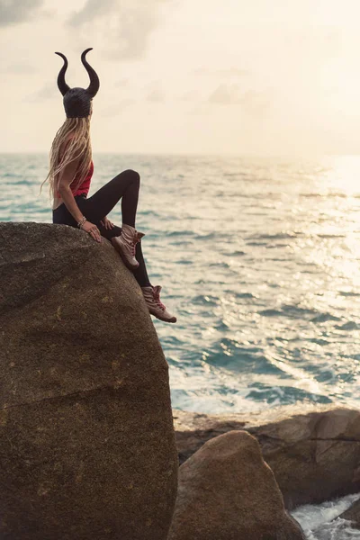 崖の海岸に角面の座席を着て夕日を楽しむ女性 — ストック写真