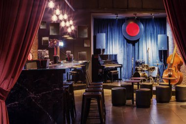 Modern jazz bar interior design, stage with black piano and cello, lamps above bar counter clipart