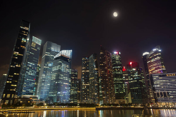 Night Sky with Moon above modern skyscrapers architecture. Business city centre skyline in Singapore