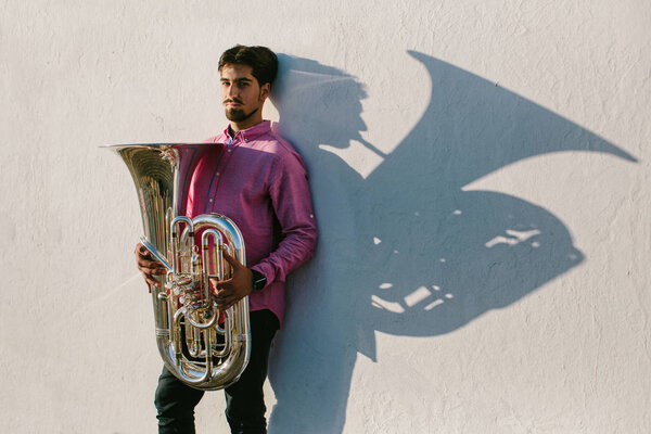 Portrait and shadow of Musician with his musical instrument tuba. White wall background