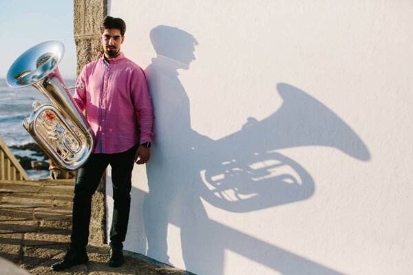 Outdoor Portrait of musician with tuba wind musical instrument. Shadow, white backgroung