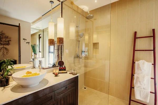 Toilet cabin in bathroom interior luxury asian style, big lamps, towels hanging on bamboo racking