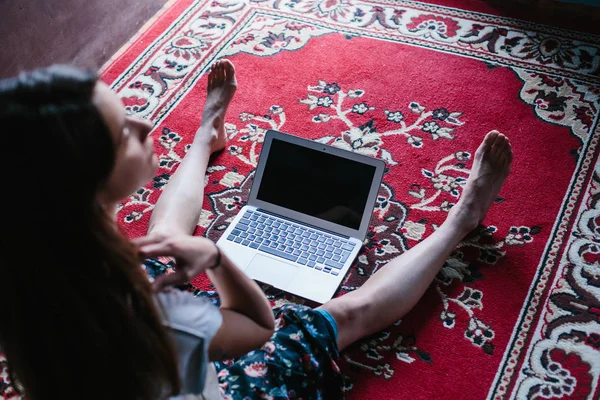若い女性のフリーランスは レッドカーペットの上にラップトップコンピュータで座っている ホームワークスペースと無料の旅行コンセプト — ストック写真
