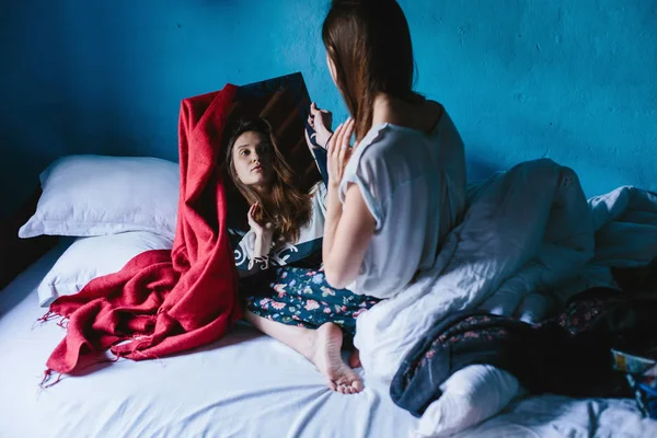 Assentos Femininos Jovens Cama Olhando Para Espelho Fundo Parede Azul — Fotografia de Stock