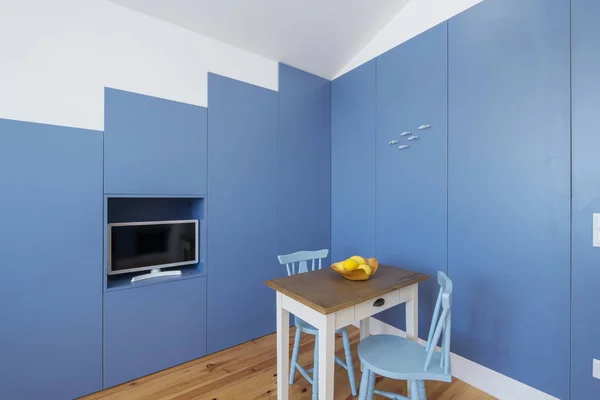 Minimal interior design kitchen in small apartment. Blue walls, yellow lemons on little table