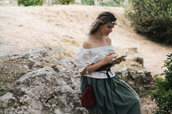 Žena Středověkém Oblečení Sedí Venku Pomocí Mobilního Telefonu — Stock fotografie