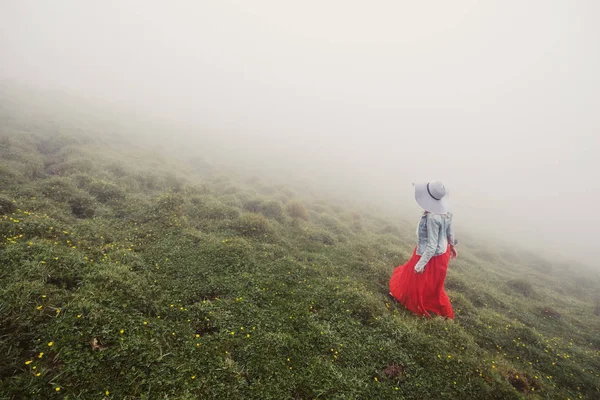 Wanita Mengenakan Gaun Merah Dan Topi Putih Berjalan Pegunungan Kabut — Stok Foto