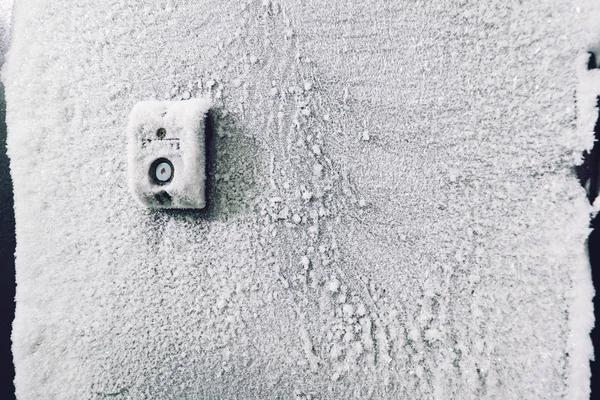 北側の建物のドアの冷凍インターホンボタン 寒い雪の冬 — ストック写真
