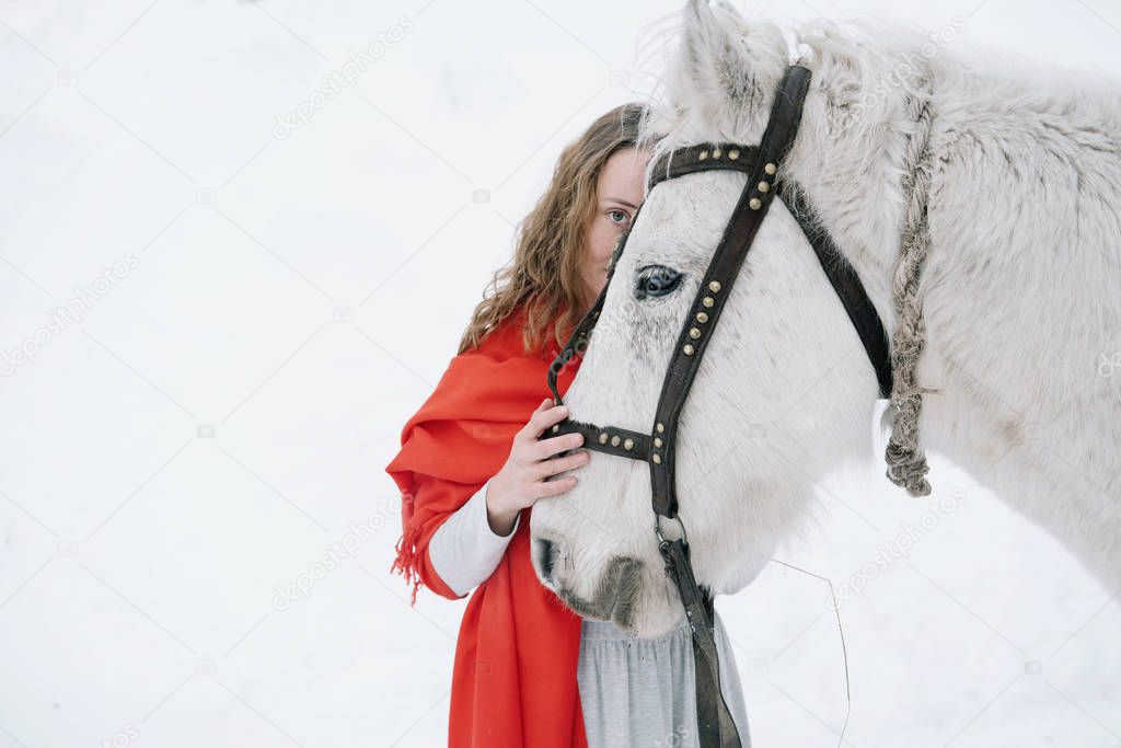 Beautiful woman with white horse in winter fir forest 