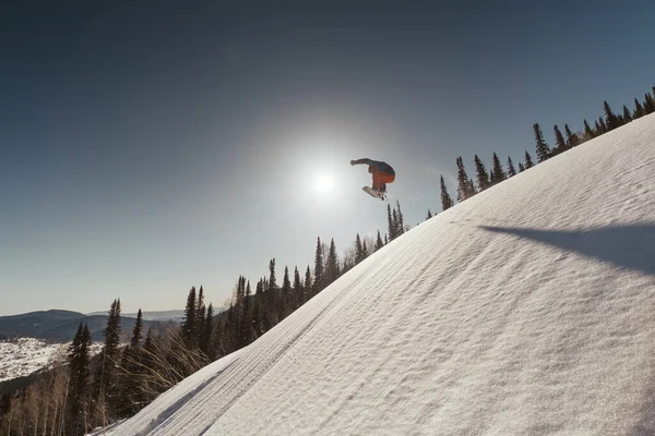 雪地滑雪场上跳跃的雪地男子的轮廓 阳光灿烂的日子在滑雪胜地 美丽的山景 — 图库照片