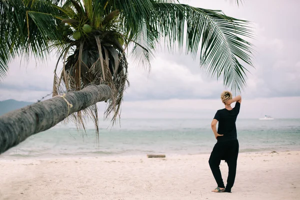 Жінка Коротким Волоссям Стоїть Морському Піску Під Пальмою Собакою Насолоджується — стокове фото
