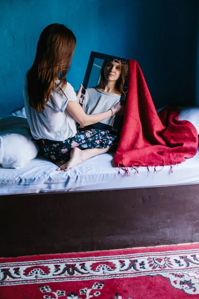 Mladá Žena Sedící Posteli Dívající Zrcadla Modrá Stěna Pozadí Červený — Stock fotografie
