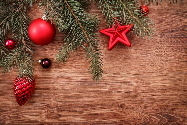 Enfeites de Natal vermelho e ramo de abeto em um fundo de madeira rústico. Cartão de Natal. Feliz Ano Novo. Vista superior com espaço de cópia — Fotografia de Stock