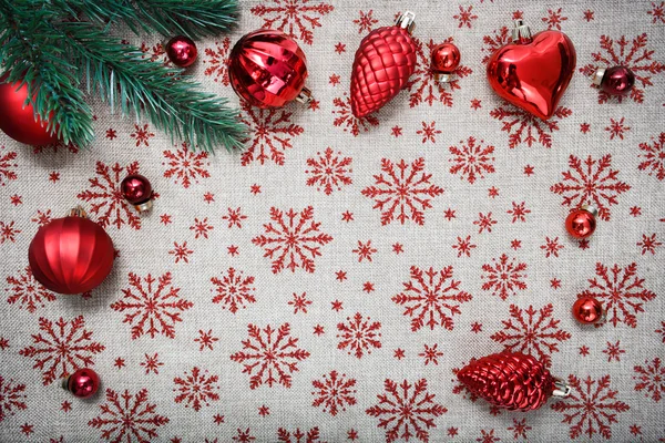 Adornos rojos de Navidad y árbol de Navidad sobre fondo de lona con copos de nieve de brillo rojo. Tarjeta de Navidad. Tema Feliz Año Nuevo. Espacio para texto — Foto de Stock