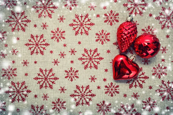 Enfeites de Natal vermelho, cones, coração, bolas e árvore de xmas sobre tela de fundo com flocos de neve de brilho vermelho. Cartão de Natal. Feliz Ano Novo. Espaço para texto — Fotografia de Stock