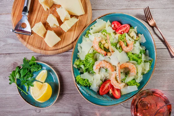 Karides salatası parmesan peyniri, kruton, domates, karışık yeşillik, marul ve ahşap arka plan üzerinde şarap ile. Sağlıklı gıda. Üstten Görünüm