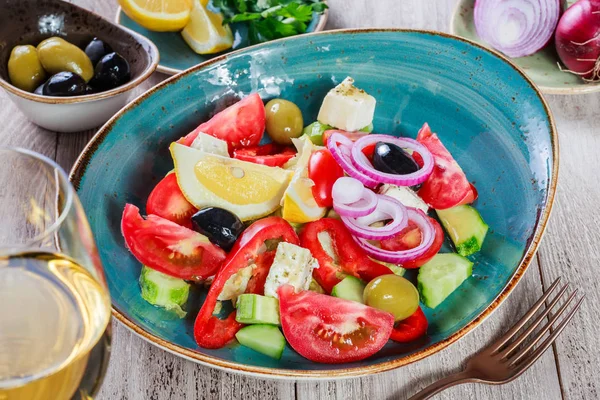 Griechischer Salat aus Bio-Gemüse mit Tomaten, Gurken, roten Zwiebeln, Oliven, Feta-Käse und einem Glas Wein auf Holzgrund. Ansicht von oben — Stockfoto