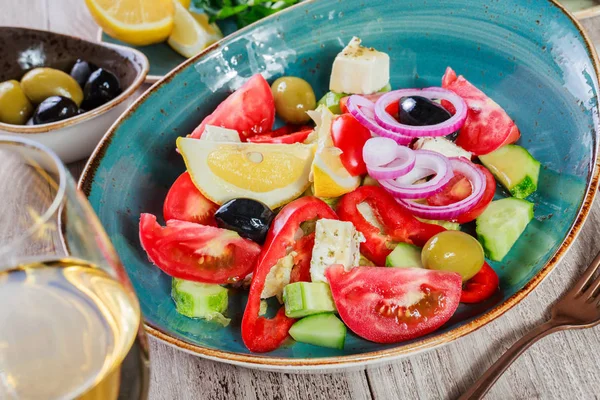 Griechischer Salat aus Bio-Gemüse mit Tomaten, Gurken, roten Zwiebeln, Oliven, Feta-Käse und einem Glas Wein auf Holzgrund. Ansicht von oben — Stockfoto