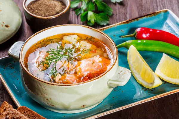 Sopa de pescado con salmón y camarones, eneldo, papas, limón, pimientos y pan sobre fondo de madera oscura, comida saludable — Foto de Stock