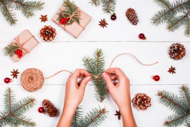 Çam dalları, çam kozalakları, skein jüt, kırmızı süslemeleri ile Noel arka plan. Eller. Noel ve mutlu yeni yıl kompozisyon. Düz yatıyordu, en iyi görünümü