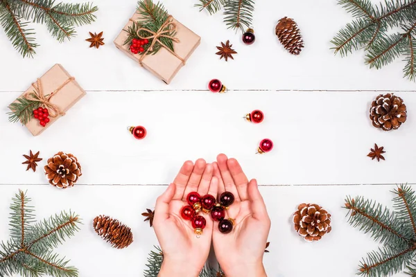 Vánoční pozadí s vánoční dárek, jedle větve, šišky, červená dekorace. Ženské ruce. Vánoce a šťastný nový rok složení. Plochá ležel, horní pohled — Stock fotografie