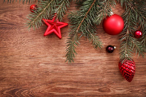 Enfeites de Natal vermelho e ramo de abeto em um fundo de madeira rústico. Cartão de Natal. Feliz Ano Novo. Vista superior com espaço de cópia — Fotografia de Stock