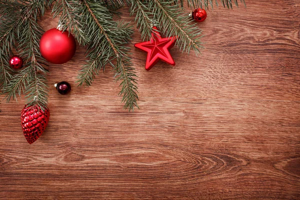 Adornos rojos de Navidad y rama de abeto sobre un fondo rústico de madera. Tarjeta de Navidad. Feliz Año Nuevo. Vista superior con espacio de copia — Foto de Stock