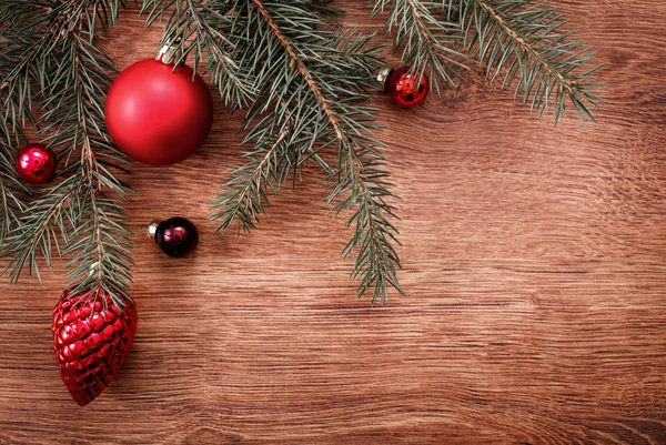 Rode Kerst ornamenten en vertakking van de beslissingsstructuur van het fir op een rustieke houten achtergrond. Xmas card. Gelukkig Nieuwjaar. Bovenaanzicht met kopie ruimte — Stockfoto