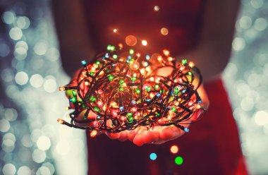 Çok renkli Noel ışık süslemeleri tatil koyu arka plan üzerinde tutan eller. Noel ve yeni yıl tema. Tonlama.
