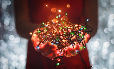 Çok renkli Noel ışık süslemeleri tatil koyu arka plan üzerinde tutan eller. Noel ve yeni yıl tema. Tonlama.