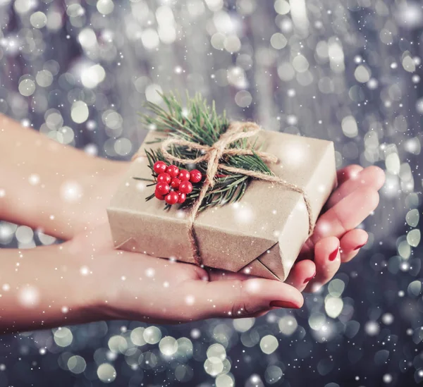 여성 손 빛나는 크리스마스 배경 전나무 나무의 분기와 크리스마스 선물 상자를 들고. 크리스마스 선물 그리고 훈장입니다. 토닝 — 스톡 사진