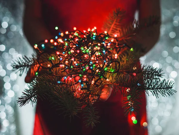Kvinnliga händer som håller mångfärgade ljus juldekorationer på mörka holiday bakgrund. Xmas och nyår tema. Toning. — Stockfoto
