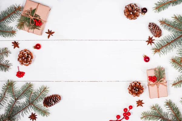 Sfondo natalizio con regalo di Natale, rami di abete, pigne, fiocchi di neve, decorazioni rosse. Natale e Felice Anno Nuovo composizione. Posto per il testo. Posa piatta, vista dall'alto — Foto Stock