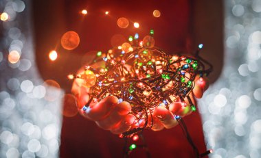 Çok renkli Noel ışık süslemeleri tatil koyu arka plan üzerinde tutan eller. Noel ve yeni yıl tema. Tonlama.