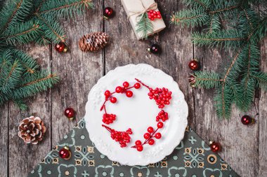 Noel hediye, çam kozalakları, kırmızı süslemeleri, çam dalları ile ahşap arka plan üzerinde Noel çelenk plakalı. Noel ve mutlu yeni yıl kompozisyon. Düz yatıyordu, en iyi görünümü