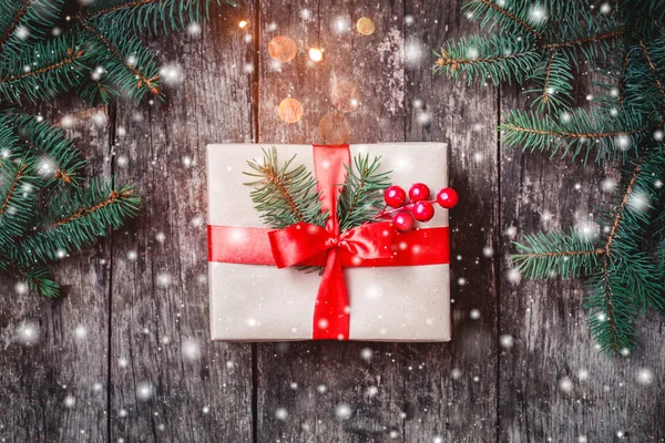 De doos van de gift van Kerstmis met rood lint, Fir takken, sneeuwvlokken op houten achtergrond. Xmas en gelukkig Nieuwjaar samenstelling. Plat lag, top uitzicht — Stockfoto