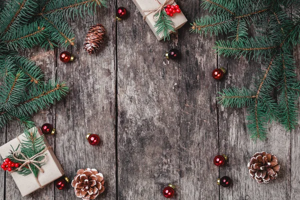 Fundo de Natal com presente de Natal, cones de pinho, decorações vermelhas em fundo de madeira com ramos de abeto. Composição de Natal e Feliz Ano Novo. Deitado plano, vista superior — Fotografia de Stock
