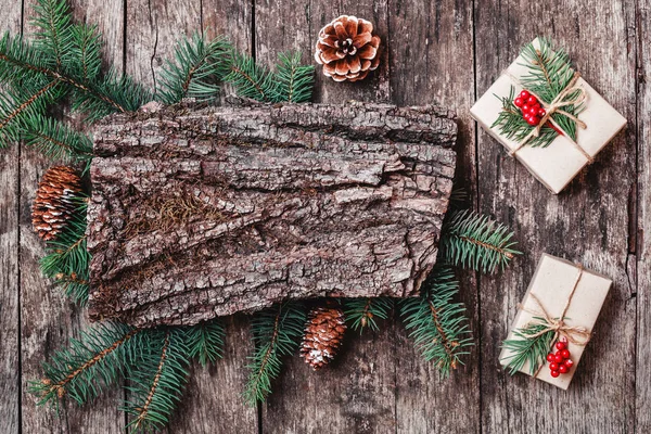 Vánoční složení s vánoční dárky, texturou kůry, tužka, jedle větve, šišky na dřevěné pozadí. Vánoce a šťastný nový rok karty. Plochá ležel, horní pohled — Stock fotografie