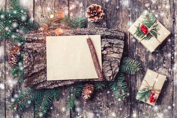 Carta de Navidad sobre fondo de madera con regalos de Navidad, textura de corteza, lápiz, ramas de abeto, conos de pino, decoraciones rojas. Navidad y Feliz Año Nuevo composición. Piso tendido, vista superior — Foto de Stock