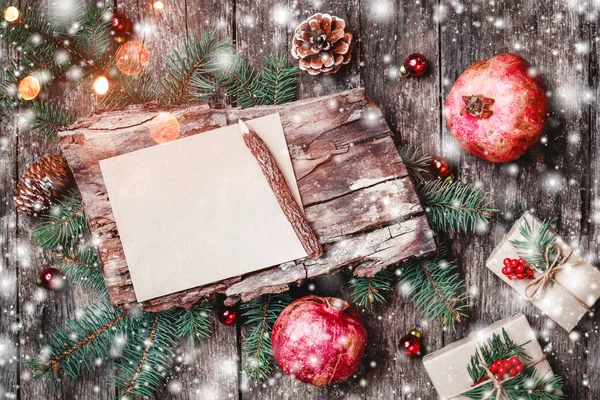 Carta de Navidad sobre fondo de madera con regalos de Navidad, textura de corteza, granada, ramas de abeto sobre fondo de madera. Navidad y Feliz Año Nuevo. Piso tendido, vista superior — Foto de Stock