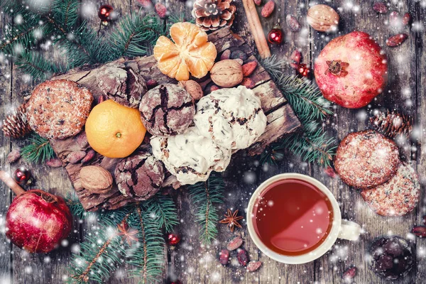 Vánoční přání. Vánoční Cookies Čokoláda, čaj, granátové jablko, mandarinky, oříšky, kakaové boby, větve jedle na dřevěné zasněžené pozadí. Vánoce a šťastný nový rok karty. Pohled shora, Selektivní ostření — Stock fotografie