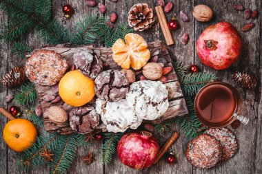 Noel kartı. Çerezler çikolata, çay, nar, mandalina, fındık, kakao çekirdekleri, çam dalları ahşap arka plan üzerinde. Noel ve mutlu yeni yıl tema. Üstten Görünüm, seçici odak