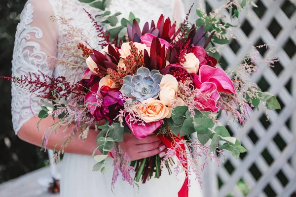 Ramo de boda con tulipanes rosados, bayas y cintas en las manos de la novia . — Foto de Stock