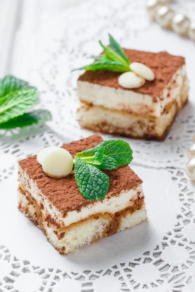 Mini cakes tiramisu with white chocolate, cocoa and candies on light background close up. Delicious dessert and candy bar.