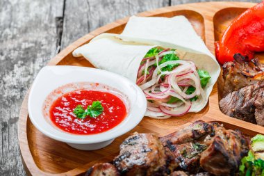 Çeşitli lezzetli ızgara et ve sebze taze salata ve kesme tahtası üzerinde ahşap arka plan barbekü sosu ile kapatın. Sıcak et yemekleri. Üstten Görünüm