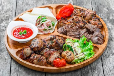 Çeşitli lezzetli ızgara et ve sebze taze salata ve kesme tahtası üzerinde ahşap arka plan barbekü sosu ile kapatın. Sıcak et yemekleri. Üstten Görünüm