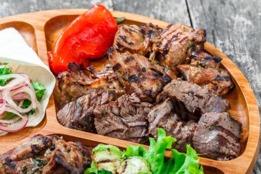 Çeşitli lezzetli ızgara et ve sebze taze salata ve kesme tahtası üzerinde ahşap arka plan barbekü sosu ile kapatın. Sıcak et yemekleri. Üstten Görünüm
